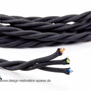 Könnte beinhalten: Schwarz verdrilltes Elektrokabel mit freiliegenden farbigen Drähten am Ende. Das Kabel ist eng gewebt und wirkt langlebig. Das Bild enthält auch die Website-Adresse www.design-restoration-spares.de.