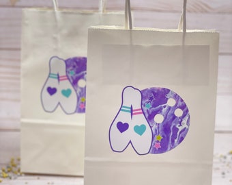 May include: Two white paper gift bags with handles. The bags have a purple and white bowling pin and ball design with hearts and stars.
