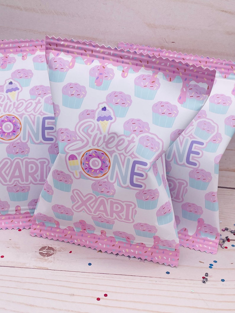 May include: Pink and white treat bags with a cupcake pattern and the text "Sweet One Xari".