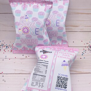 May include: Pink and white favor bags with a donut and ice cream cone design. The bags have the text "Sweet One" and "Thanks for Coming". A QR code is printed on the bag with the text "Scan Me! @mypaperzone".