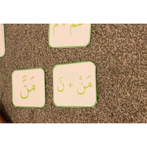 Puede incluir: Dos tarjetas blancas con bordes verdes. La primera tarjeta tiene la palabra &aacute;rabe "مي" escrita en ella. La segunda tarjeta tiene las palabras &aacute;rabes "مي +  تا" escritas en ella.