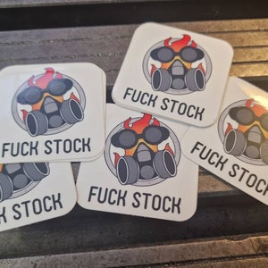 以下が含まれることがあります： ガス・マスクのデザインと「FUCK STOCK」の文字が入った正方形のステッカーがいくつかあります。 ガス・マスクは炎とサングラスの円の中にあります。 ステッカーは白で光沢があります。