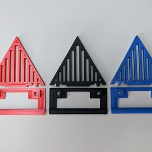 May include: Three 3D printed triangular objects with a geometric pattern. The objects are in red, black, and blue.