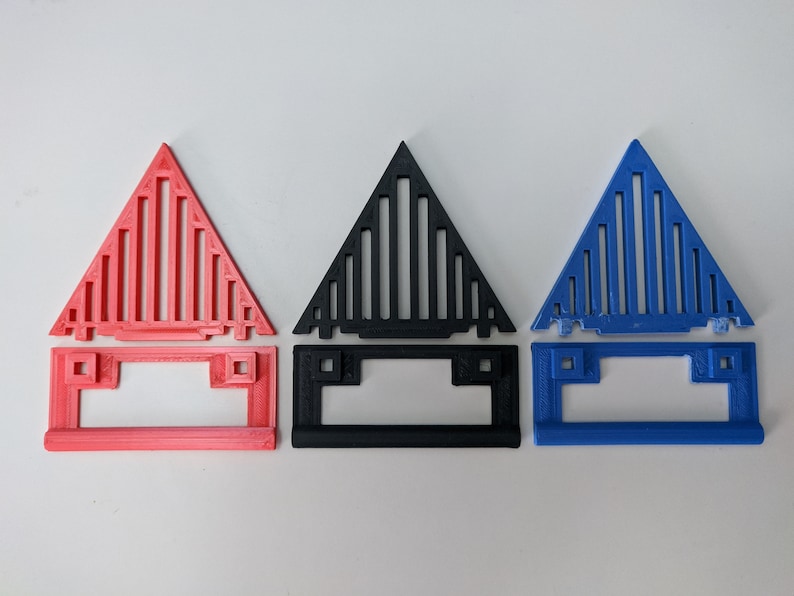 May include: Three 3D printed triangular objects with a geometric pattern. The objects are in red, black, and blue.