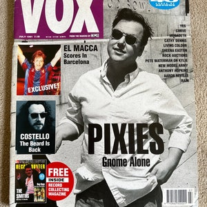 May include: A magazine cover for Vox, a music and movie magazine. The cover features a black and white photo of a man wearing a white shirt and sunglasses. The magazine title is in large, bold, purple letters. The cover also features the text "Pixies Gnome Alone" in large, bold, black letters.