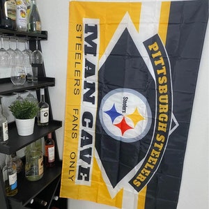 May include: A black and yellow Pittsburgh Steelers flag with the words "Man Cave Steelers Fans Only" printed on it. The flag features the Steelers logo with a black and white football helmet and the words "Pittsburgh Steelers" in a curved arc.