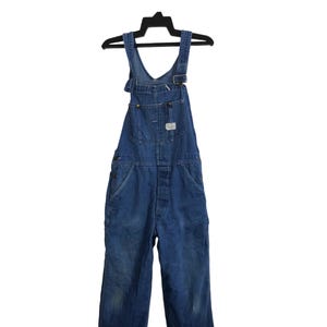 May include: A pair of blue denim dungarees with a single front pocket and adjustable straps.