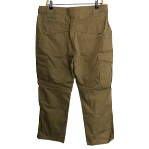 Pu&ograve; includere: Pantaloni cargo color kaki appesi a una gruccia di legno. I pantaloni hanno pi&ugrave; tasche sui lati e sul retro. Il tessuto sembra essere un materiale resistente e di peso medio.