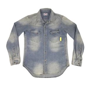 May include: Pale blue denim shirt with long sleeves, two chest pockets, and a button-down front. The shirt has a faded wash effect and a classic Western style. A small yellow tag is attached.