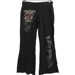 Könnte beinhalten: Schwarze Jogginghose mit einem Vintage-Grafikdruck des Rolling-Stones-Logos auf dem linken Bein und dem Bandnamen auf dem rechten Bein.