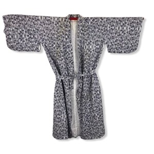 May include: A kimono-style robe with a floral pattern in navy and white. The robe features wide sleeves and a matching belt. The interior lining is visible, and the robe is open at the front.