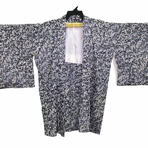 Puede incluir: Un kimono con estampado en blanco y negro, cuello blanco y mangas largas.