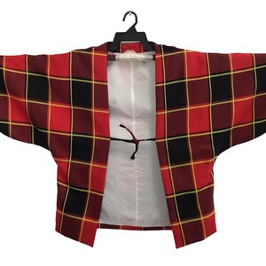 May include: A red and black plaid kimono with a white lining and a black tie closure.