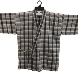 May include: A grey and black checked kimono with a tie belt. The kimono has a pocket on the left side and decorative stitching on the sleeves.