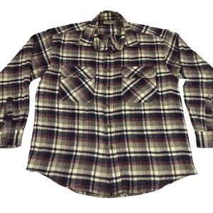 Pode incluir: Uma camisa de flanela xadrez com botões e mangas compridas. A camisa tem gola, dois bolsos no peito e punhos com botões. O design xadrez incorpora tons de cinza, azul marinho, creme e bordô.