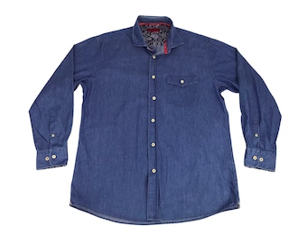 May include: A long-sleeved denim shirt in a medium blue hue. The shirt features a classic collar, button-down front, and two chest pockets. The inside collar and cuffs have a paisley pattern. The shirt is a casual wear item.