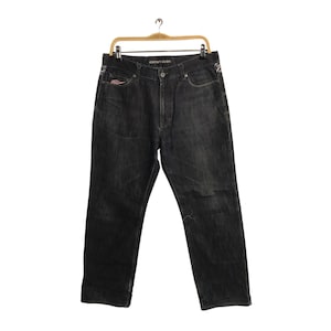 May include: Dark gray Element Denim jeans hanging on a wooden hanger. The jeans have a classic five-pocket design, a button and zipper closure, and the brand name is visible on the waistband. The jeans have a slightly faded appearance.