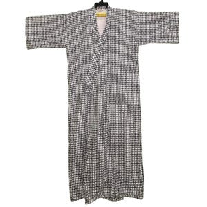 May include: A long, open-front robe with a black and white chequered pattern. The robe features wide sleeves and a V-neck. It is suspended from a black hanger.