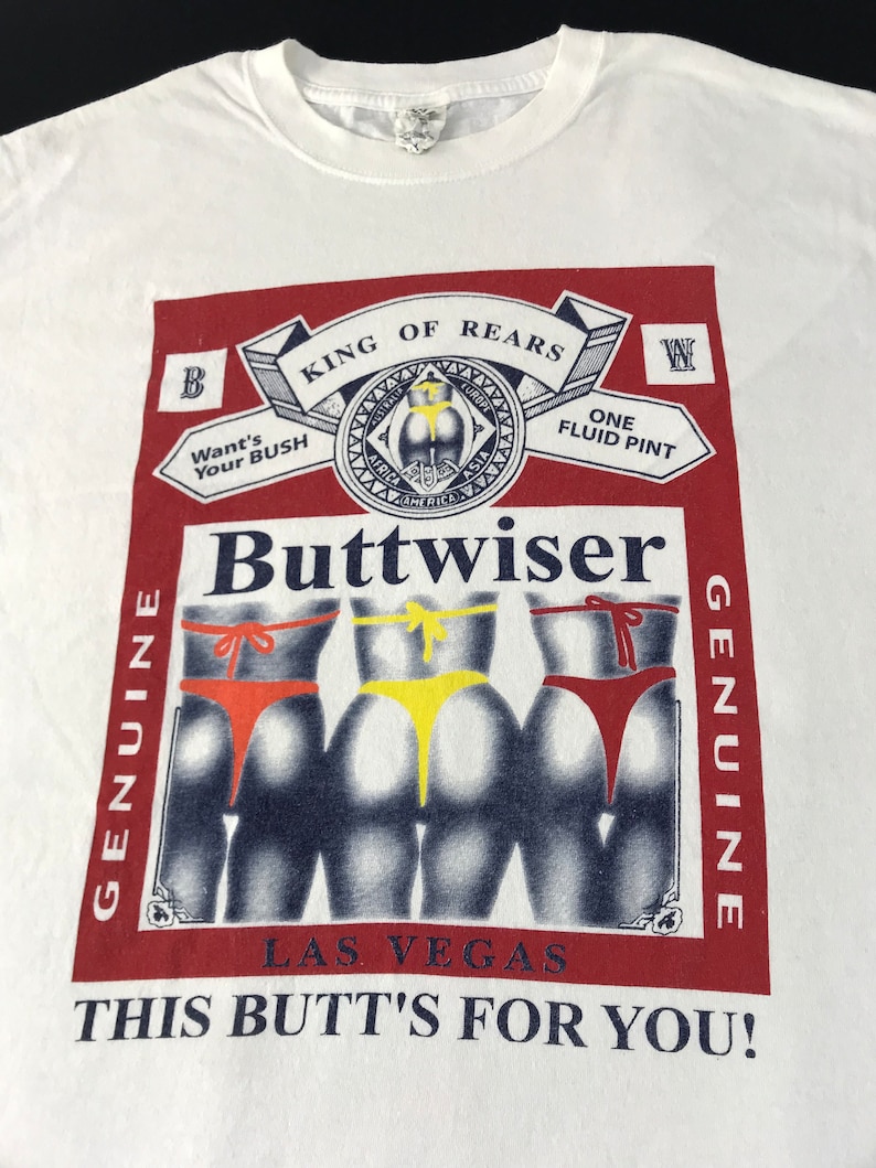 May include: White t-shirt with a graphic parody of a beer label. The design features the word "Buttwiser" and illustrations of three posteriors in colorful thong underwear. Text includes "King of Rears" and "This Butt's For You!"
