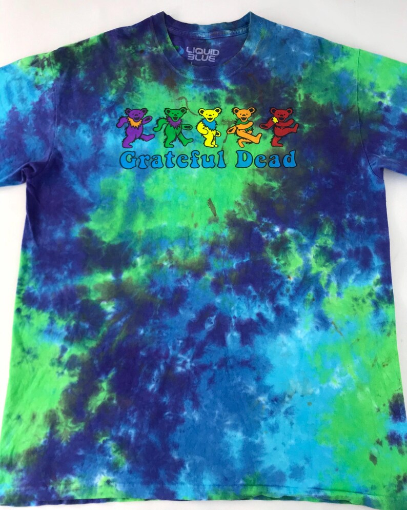 Puede incluir: Una camiseta tie-dye con un patr&oacute;n de remolino azul, verde y morado. La camiseta presenta un gr&aacute;fico de osos bailando y el texto "Grateful Dead" en blanco.