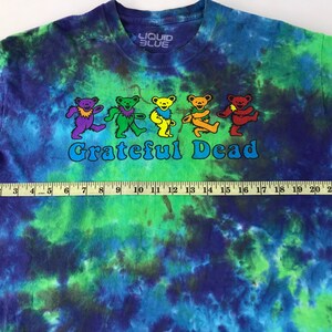 Puede incluir: Una camiseta tie-dye con un esquema de color azul, verde y morado. La camiseta presenta un gr&aacute;fico de osos bailando y el texto "Grateful Dead".