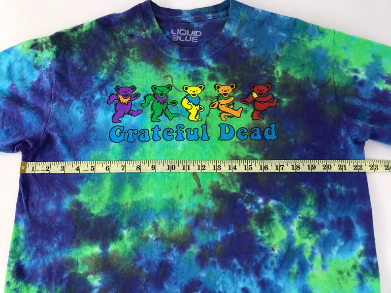 Puede incluir: Una camiseta tie-dye con un esquema de color azul, verde y morado. La camiseta presenta un gr&aacute;fico de osos bailando y el texto "Grateful Dead".