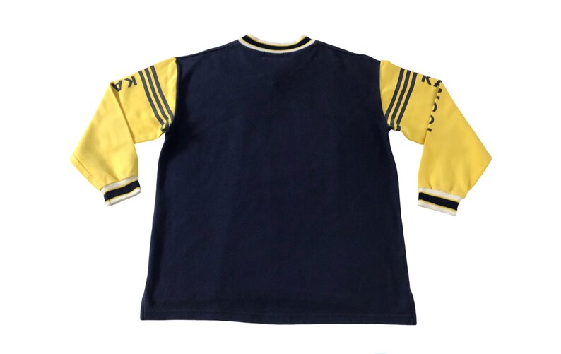 May include: Navy blue long-sleeved shirt with yellow sleeves. The sleeves have black stripes and the word "KANGOL" printed on them. The shirt has a crew neck with black and white trim.