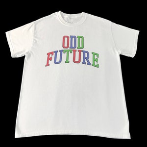May include: White t-shirt with the text "ODD FUTURE" in a colorful, arched design. The text is in red, blue, and green. The shirt is made of a soft material and has short sleeves.