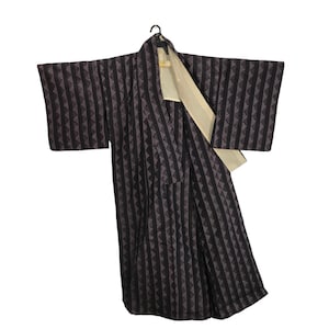 May include: A dark kimono with a geometric pattern of triangles and vertical stripes. The kimono has wide sleeves and a cream-coloured lining. It is hanging on a black hanger against a white background.