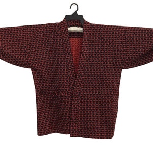 Puede incluir: Un kimono de manga larga con un patrón negro y rojo.