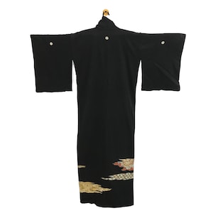 May include: A black kimono with wide sleeves, displayed on a wooden hanger. The garment features decorative floral patterns in gold, red, and white near the hem and small white floral accents on the shoulders.