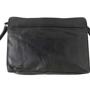 May include: Black leather clutch bag with a wrist strap. The rectangular bag features a zip closure and a small pocket. The leather has a textured finish. A simple and elegant accessory for everyday use.