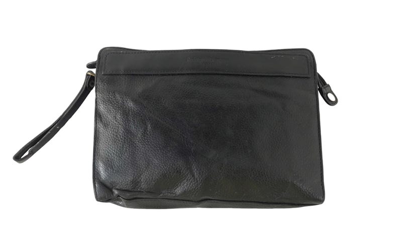 May include: Black leather clutch bag with a wrist strap. The rectangular bag features a zip closure and a small pocket. The leather has a textured finish. A simple and elegant accessory for everyday use.