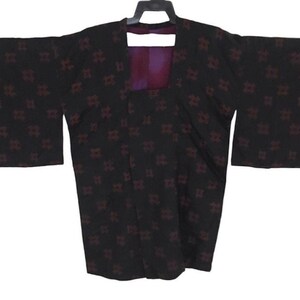 May include: A black kimono with a red and white geometric pattern. The kimono has long sleeves and a wide collar.