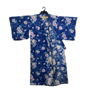 May include: A blue floral kimono with a white and pink flower pattern, hanging on a black hanger. The garment features wide sleeves and a wrap-around design, characteristic of Japanese traditional clothing.
