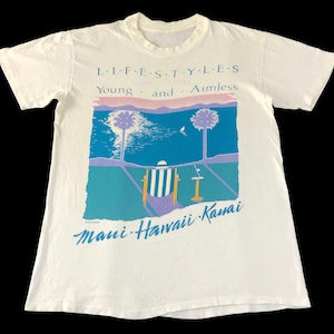 Puede incluir: Camiseta blanca con un estampado gráfico de palmeras, una silla de playa y el texto "LIFESTYLES Young and Aimless Maui Hawaii Kauai".