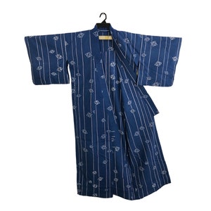 May include: A navy blue kimono with a white geometric pattern of diamonds and vertical stripes. The traditional Japanese garment is hanging on a black hanger against a white background. The kimono has wide sleeves and a wrap-around design.