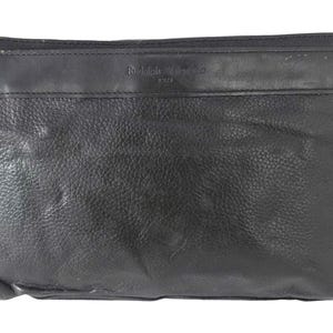 May include: Black leather clutch bag with a wrist strap and a zip closure. The bag has a rectangular shape with a textured surface. The brand name is embossed on the top.