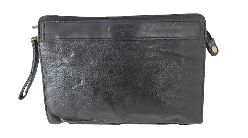 May include: Black leather clutch bag with a wrist strap and a zip closure. The bag has a rectangular shape with a textured surface. The brand name is embossed on the top.
