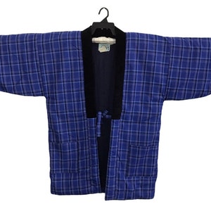 May include: Blue plaid kimono-style jacket with a black collar and trim. The jacket has long sleeves and a tie closure. The fabric has a quilted appearance. The jacket is hanging on a black hanger.