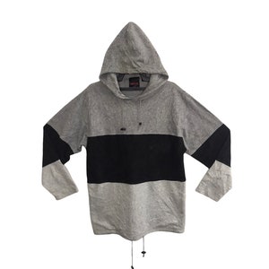 May include: A gray hooded sweatshirt with a black horizontal stripe across the chest and black sleeves. The sweatshirt has a drawstring at the hood and a drawstring at the bottom hem.