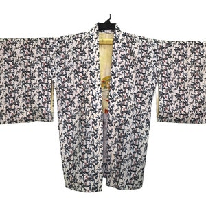Peut inclure: Un kimono blanc avec un motif floral noir et rouge. Le kimono a de longues manches et est ouvert à l'avant.
