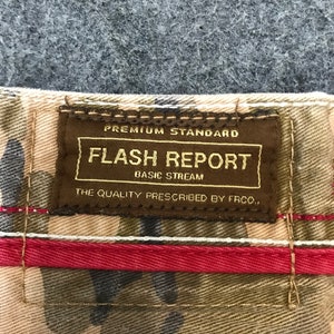 May include: A brown label with the text "Premium Standard Flash Report Basic Stream The Quality Prescribed by FRCO." on a camouflage fabric background.
