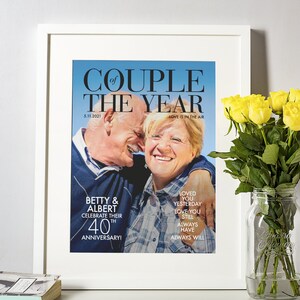 May include: A framed photo of an older couple celebrating their 40th anniversary. The photo is in a magazine style layout with the text "Couple of the Year" and "Love is in the air". The couple is smiling and hugging. The text below the photo reads "Betty & Albert Celebrate their 40th Anniversary!" and "Loved you yesterday, love you still, always have, always will."