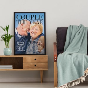 May include: A framed print of a couple celebrating their 40th anniversary. The print features a photo of the couple with the text "Couple of the Year" and "Love is in the air".