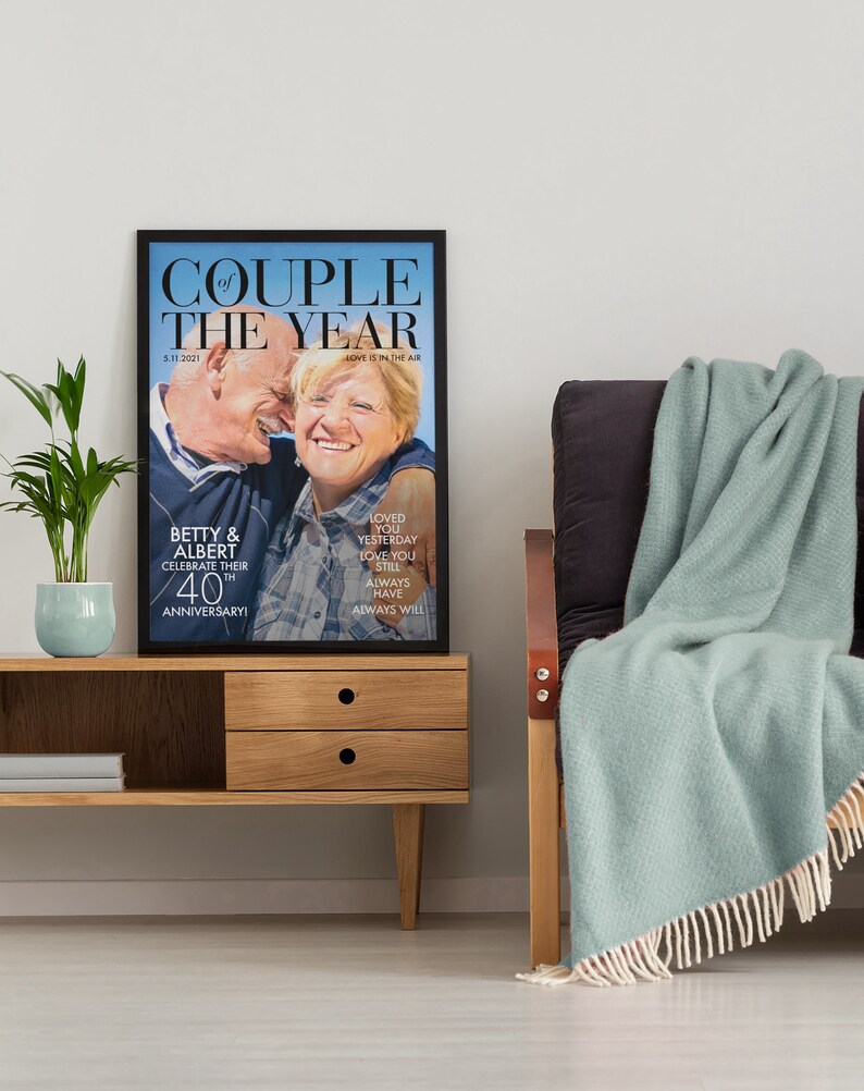 May include: A framed print of a couple celebrating their 40th anniversary. The print features a photo of the couple with the text "Couple of the Year" and "Love is in the air".
