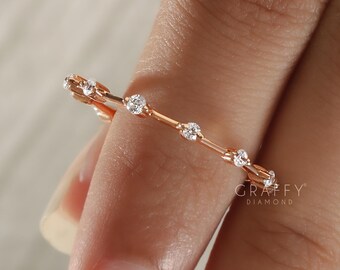 May include: A delicate rose gold ring featuring a series of small, sparkling diamonds. The ring's design is a thin band with evenly spaced gemstones. The ring is shown on a person's finger. The brand name "GRAFFY DIAMOND" is visible.