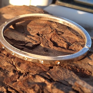 May include: A silver bangle bracelet with small clear stones set around the edge.