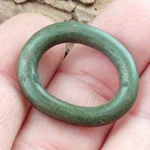 Op de afbeelding: Een groene metalen ring met een glad, afgerond oppervlak.