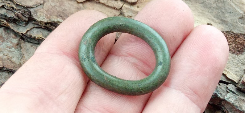 Op de afbeelding: Een groene metalen ring met een glad, afgerond oppervlak.